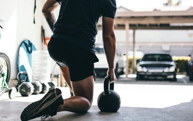 man in black t-shirt and black shorts standing on black and white basketball hoop posing for men's fitness health trends